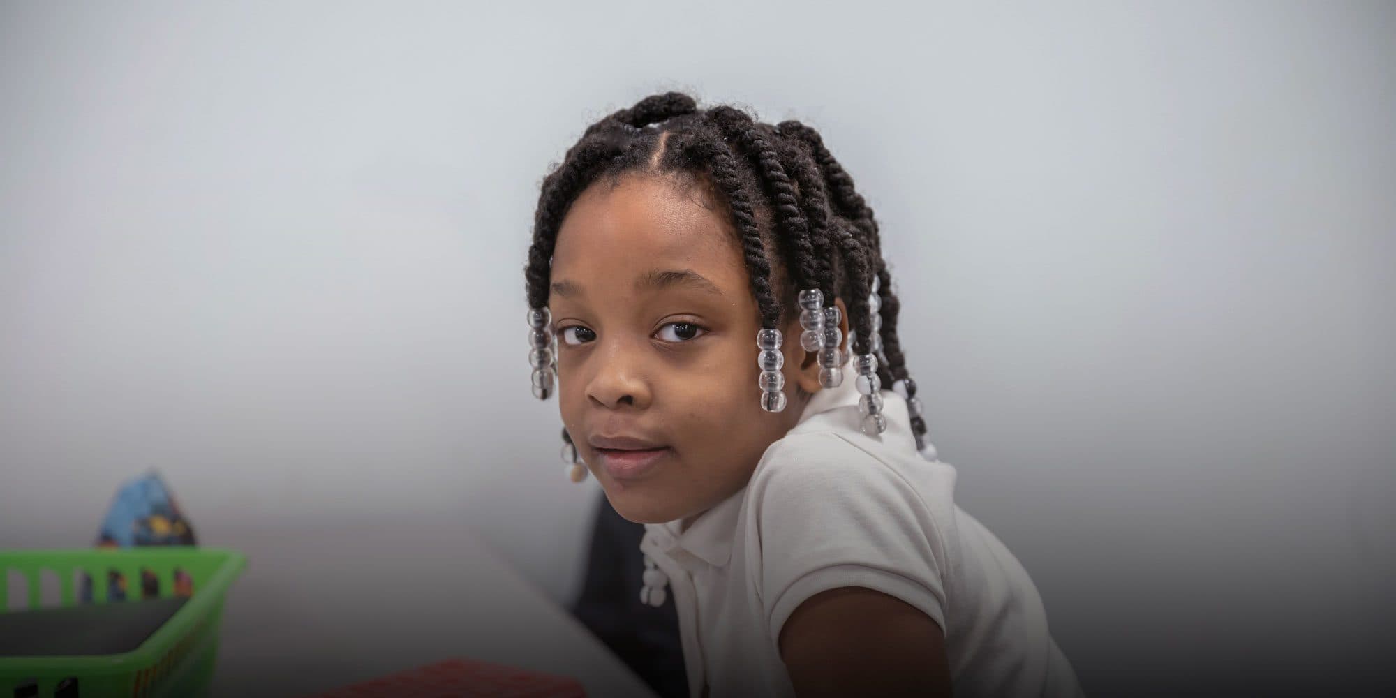 Young student with beaded braids looking toward the camera.